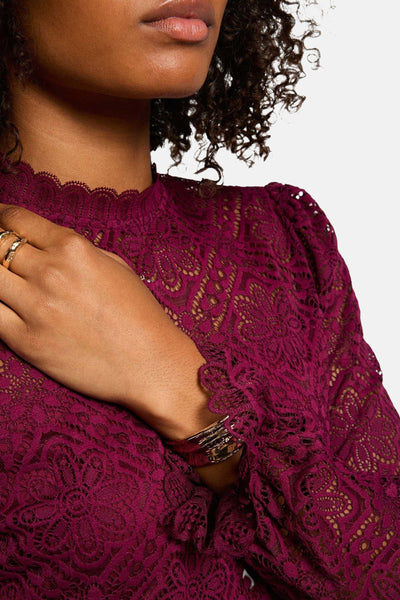 Rode blouse met lange mouwen van Morgan de Toi in bloemenkant, versierd met gouden sieraden.
