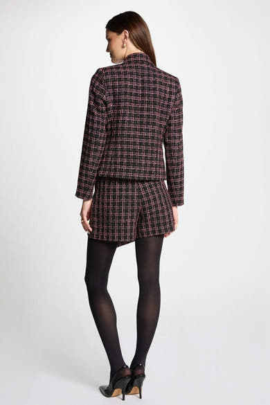 Blazer multicolore de Morgan de Toi, avec un motif à carreaux et porté avec des collants noirs et des escarpins.