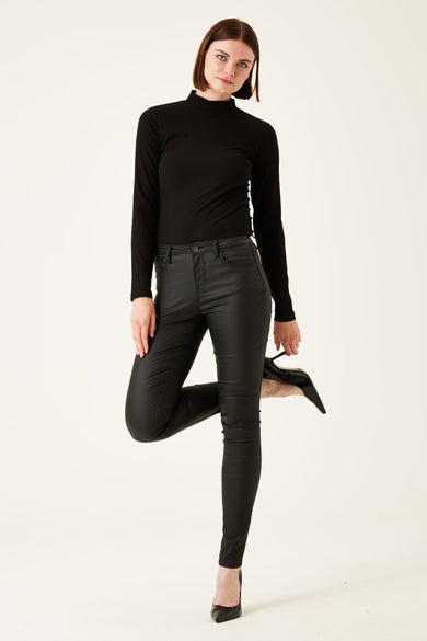 Pantalon noir enduit de chez GARCIA, porté avec un haut noir à manches longues et des escarpins noirs.