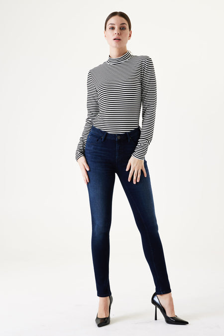Dark blue slim-fit denim jeans by Celia, shown on model with striped top and black heels, front full-length view