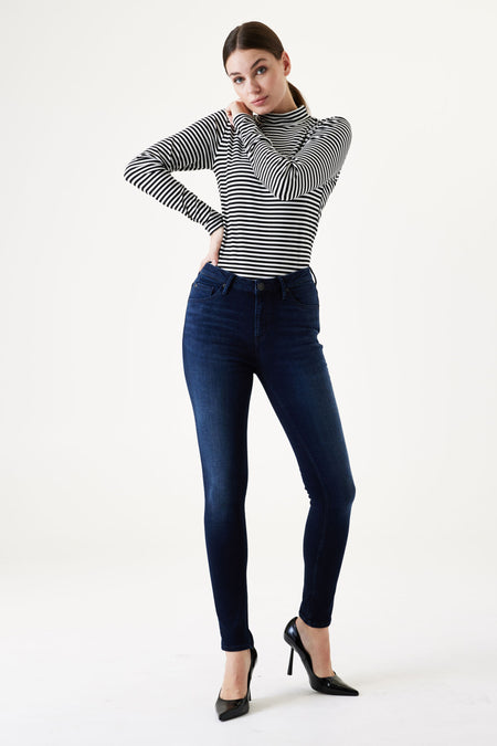 Dark blue slim-fit jeans by Celia Super Slim, featuring high waist and stretch denim, worn with striped top and black heels, full-length front view.