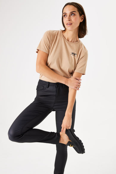 Jean slim zwart van GARCIA, gedragen met een beige t-shirt met tijgerprint en zwarte mocassins.