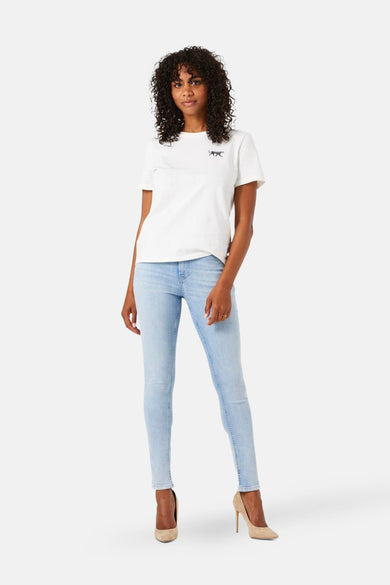 Lichtblauwe spijkerbroek van GARCIA, gedragen met een wit T-shirt en beige pumps.