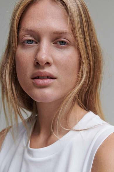 Débardeur blanc d'OPUS, porté par une femme aux cheveux blonds, avec un t-shirt blanc à col ras du cou.