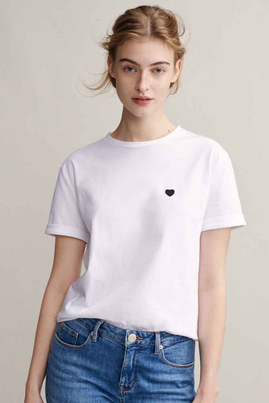 T-shirt blanc uni à manches courtes de OPUS, orné d'un petit cœur noir et porté avec un jean bleu.
