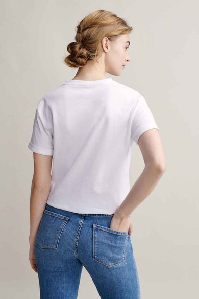 T-shirt blanc à manches courtes par OPUS, porté avec un jean bleu et coiffure chignon.