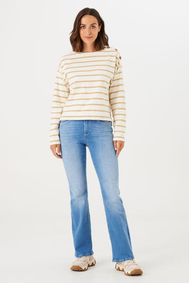 Jean évasé bleu moyen de GARCIA, coupe bootcut, porté avec un haut rayé beige et blanc et des chaussures de sport.