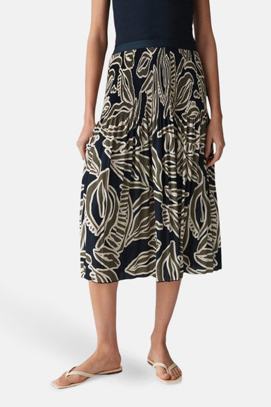 Jupe 3/4 multicolore de OPUS avec motif floral, plissée, portée avec un haut bleu marine et des sandales.
