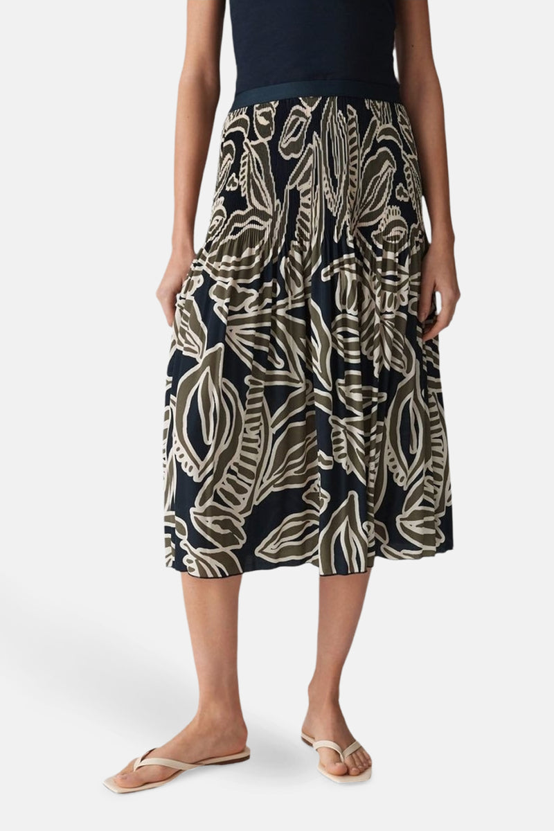 Jupe 3/4 multicolore de OPUS avec motif floral, plissée, portée avec un haut bleu marine et des sandales.
