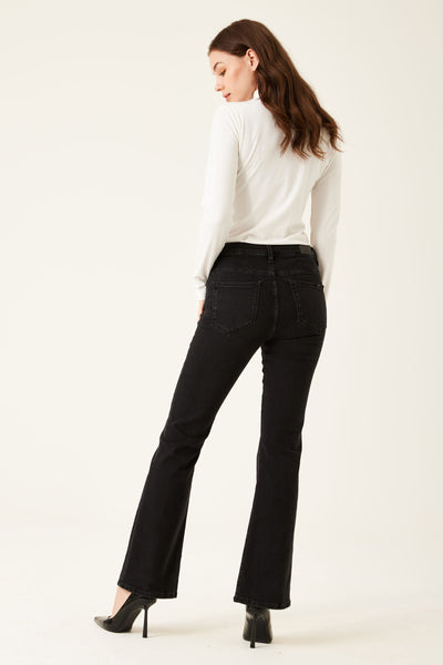 Zwarte uitlopende jeans van GARCIA, gedragen met een witte top met lange mouwen en zwarte pumps.
