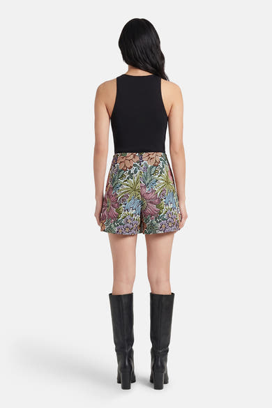 Multikleurige skort van Terra di Siena met een stijlvolle bloemenprint, gedragen met een zwarte top en laarzen.