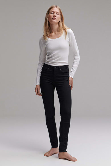 Jean slim noir d'OPUS, porté avec un haut blanc à manches longues, présenté sur un fond gris uni.