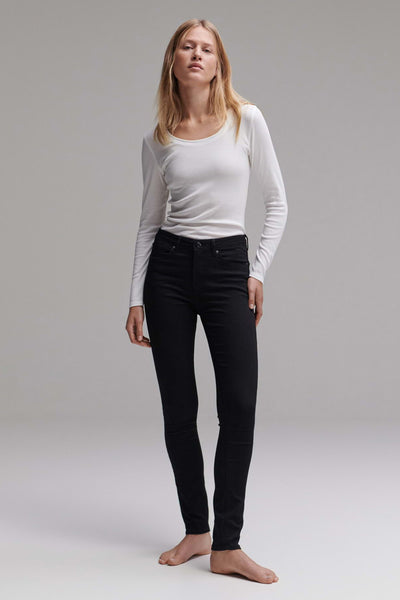 Jean slim noir d'OPUS, porté avec un haut blanc à manches longues, présenté sur un fond gris uni.