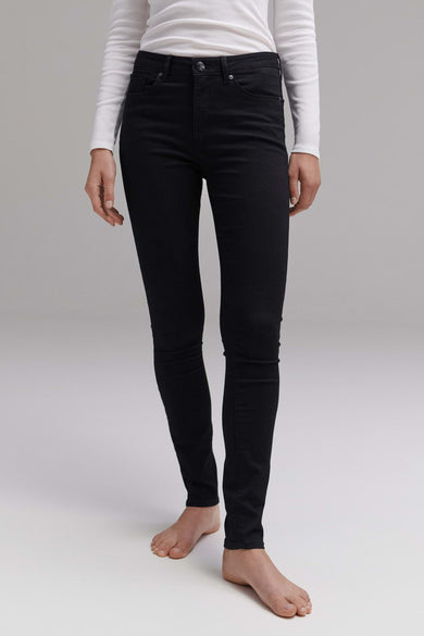 Jean slim noir de OPUS porté avec un haut blanc à manches longues, pieds nus.
