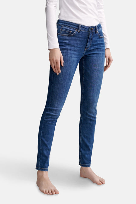 Jean skinny bleu moyen de OPUS, porté avec un haut blanc à manches longues, coupe régulière.
