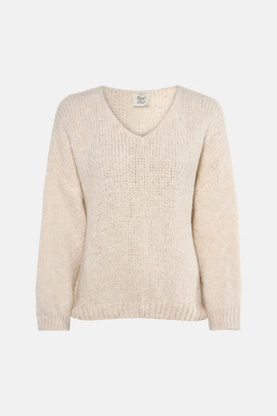 Ecru V-hals trui van Terra di Siena, gedragen met een blauwe jeans en nude pumps.