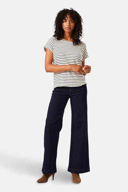 Jean large en denim bleu foncé de GARCIA, porté avec un t-shirt rayé et des bottines marron.
