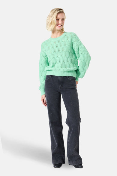 Jean large en denim noir de GARCIA, orné de détails scintillants, porté avec un pull vert menthe.

