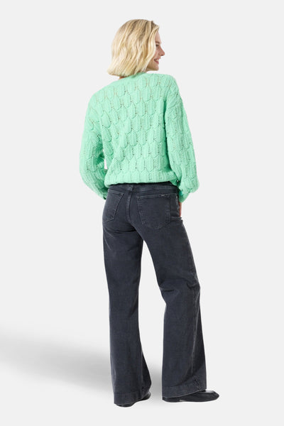 Jean large en denim noir de GARCIA, porté avec un pull en maille vert d'eau.