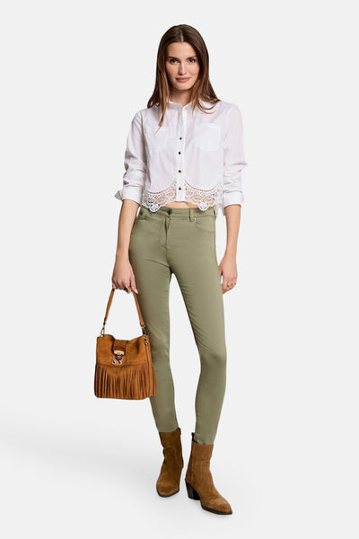 Witte blouse met lange mouwen van Morgan de Toi, met geschulpte kanten bies en gedragen met een olijfgroene broek en enkellaarsjes.