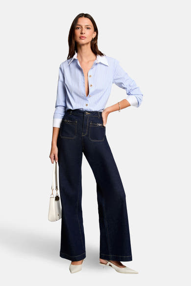 Chemise à manches longues bleue à rayures de Morgan de Toi, portée avec un pantalon foncé taille haute et des escarpins crème.
