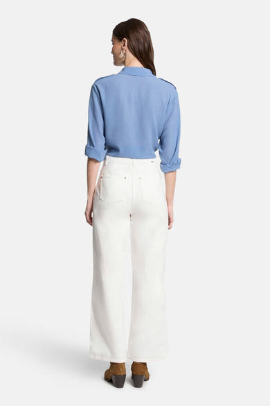 Blauwe blouse met lange mouwen van Morgan de Toi met schoudervullingen, gedragen met een witte jeans en bruine enkellaarsjes.