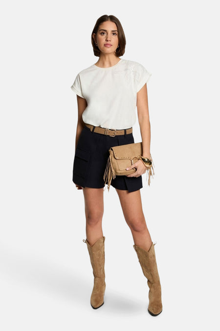 Wit T-shirt met korte mouwen van Morgan de Toi, met geborduurd bloemdetail, gedragen met een marineblauwe short, riem en suède laarzen.