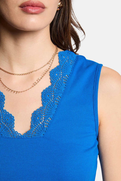 Top sans manches bleu de Morgan de Toi, avec bordure en dentelle autour de l'encolure en V, porté avec colliers dorés.