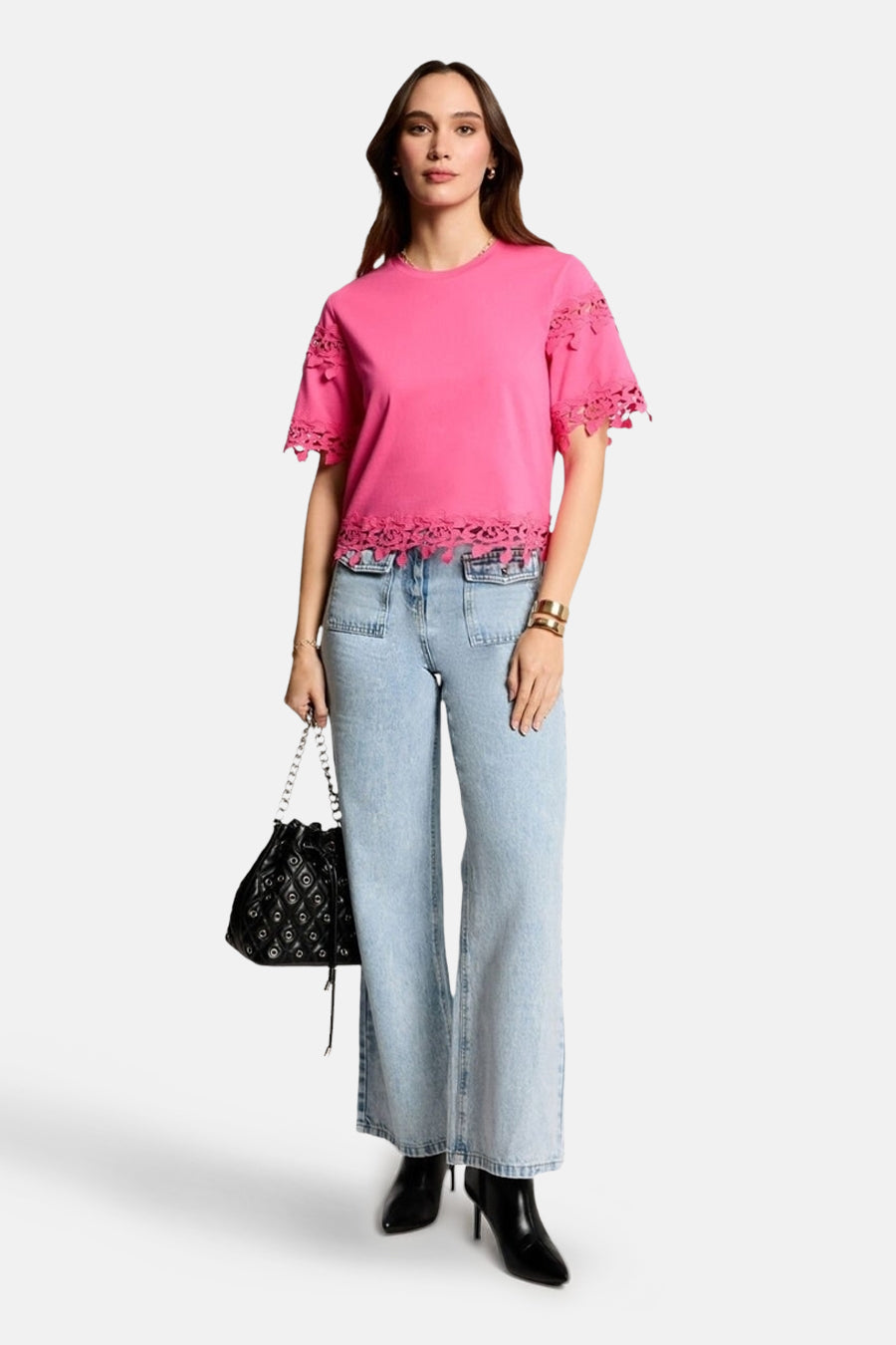Roze T-shirt met korte mouwen van Morgan de Toi, versierd met kant, gedragen met een wijde jeans en zwarte enkellaarsjes.