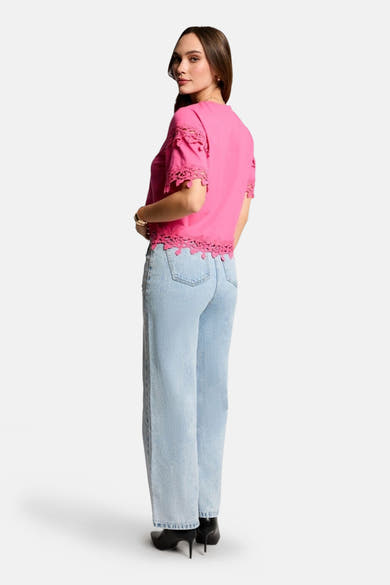 Roze T-shirt met korte mouwen van Morgan de Toi met kanten randjes, gedragen met een lichte spijkerbroek.