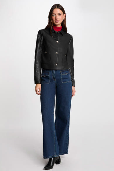 Korte zwarte jas van Morgan de Toi, met opgestikte zakken en zilveren knopen, gedragen met een blauwe jeans.