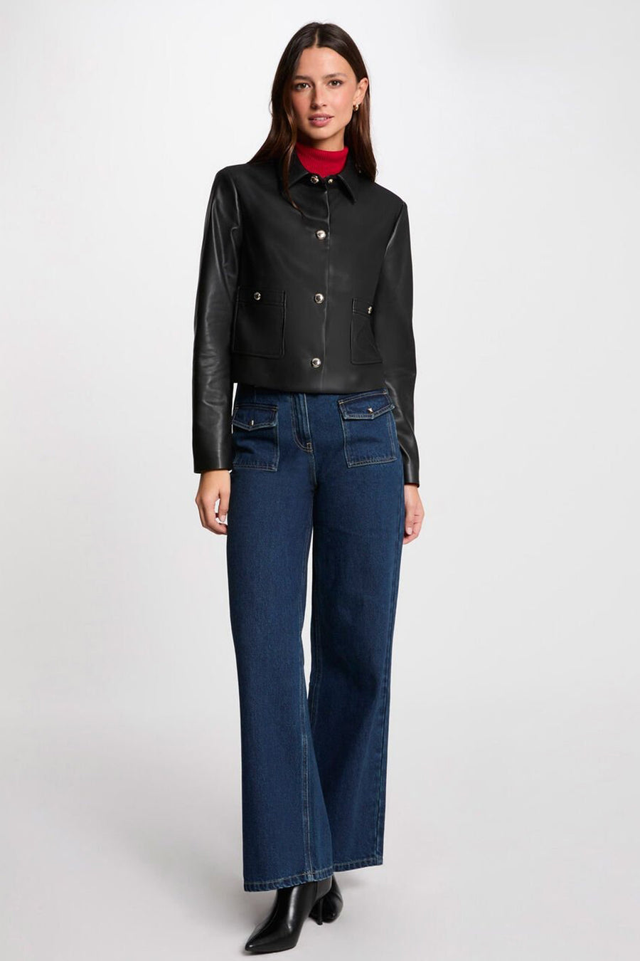 Korte zwarte jas van Morgan de Toi, met opgestikte zakken en zilveren knopen, gedragen met een blauwe jeans.