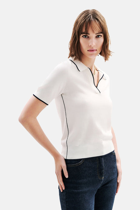 Witte korte mouw polo van Caroll, met zwarte rand, gedragen met een jeansbroek.