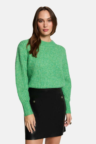 Pull à capuche vert de Morgan de Toi porté avec une jupe noire en cuir.
