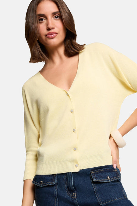 Cardigan jaune de Morgan de Toi avec manches trois-quarts et boutons décoratifs, porté avec un jean bleu.
