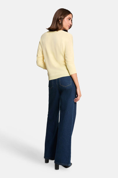 Cardigan jaune pâle de Morgan de Toi, manches 3/4 côtelées, porté avec un jean large et des talons noirs, vue de dos.