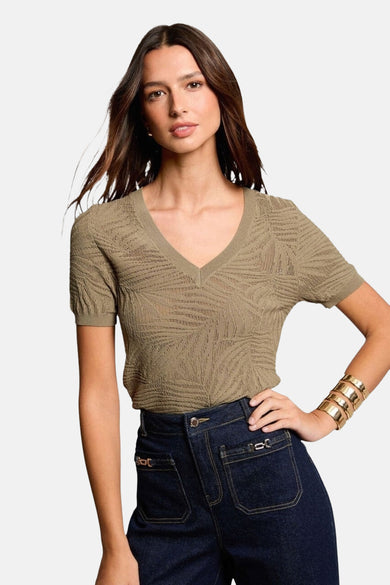 Kaki V-hals trui van Morgan de Toi met ajourpatroon, gedragen met een high-waist donkerblauwe spijkerbroek.
