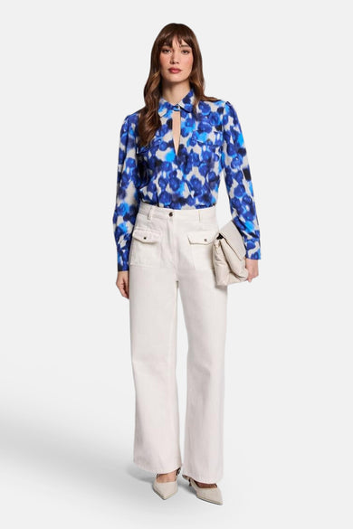 Blauwe blouse met lange mouwen van Morgan de Toi, met bloemenprint en gedragen met een witte broek.
