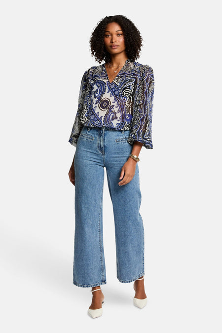 Blouse à manches longues bleue de Morgan de Toi, avec un motif cachemire bleu et noir, portée avec un jean taille haute.
