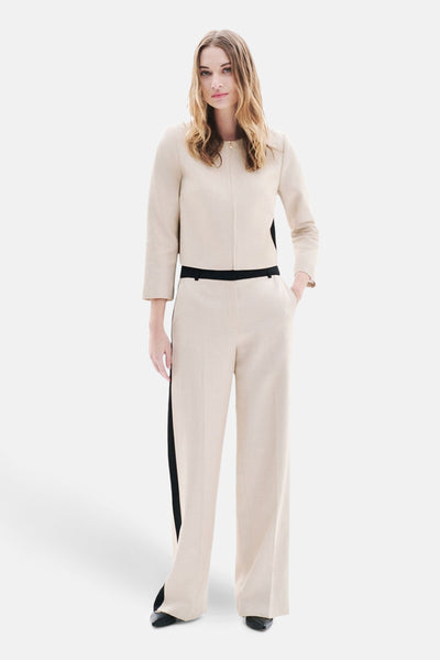Pantalon de costume beige par CAROLL, avec une bande noire contrastante sur le côté, porté avec un veste coordonnée.