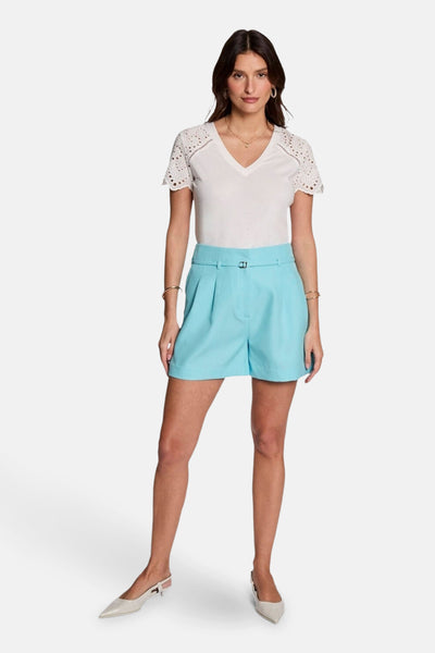 Short bleu Morgan de Toi avec ceinture intégrée, porté avec un t-shirt blanc à manches ajourées et des escarpins.