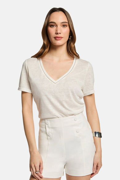 White high-waisted shorts with front button details, worn with a cream V-neck top and silver cuff bracelet, front view.