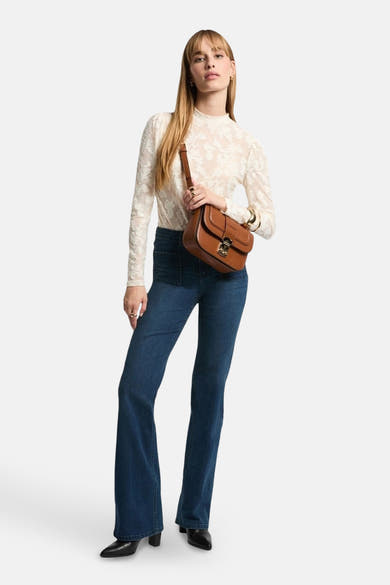 T-shirt blanc à manches longues de Morgan de Toi avec motif floral, porté avec un jean et des bottines noires.