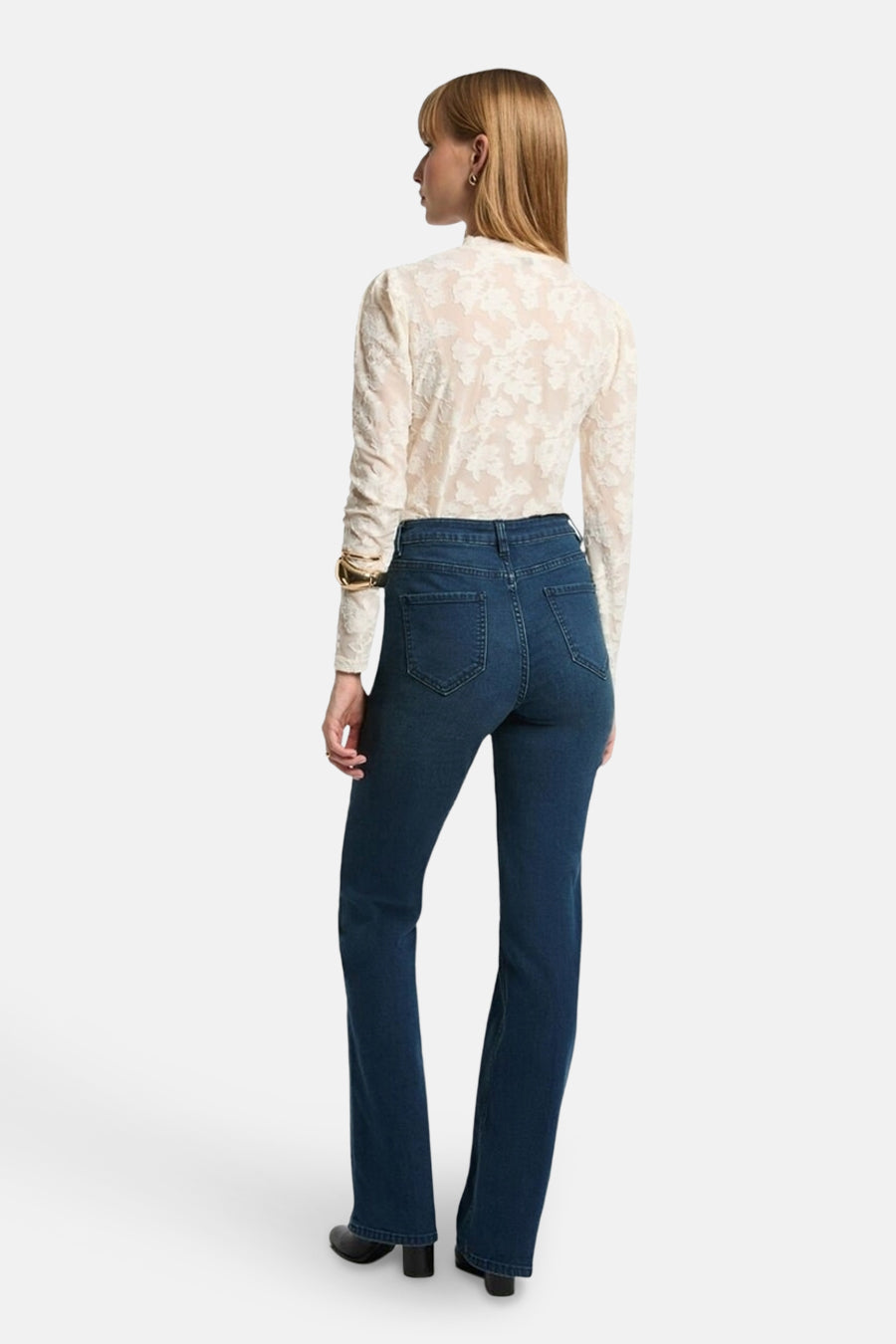T-shirt blanc à manches longues de Morgan de Toi, avec un motif floral en dentelle et porté avec un jean bleu.
