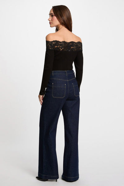 T-shirt noir à manches longues de Morgan de Toi, avec dentelle sur les épaules, porté avec un pantalon bleu en jean.