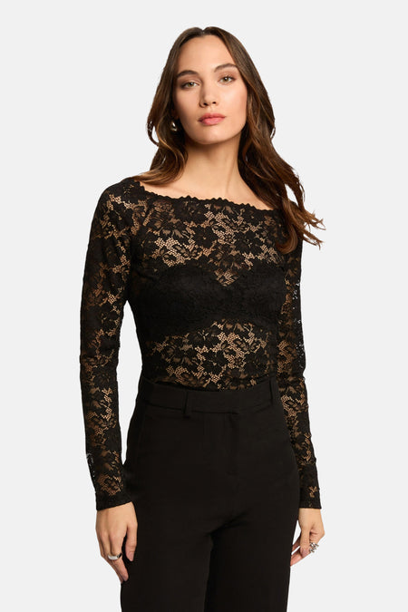 T-shirt à manches longues noir de Morgan de Toi en dentelle florale transparente, porté avec un pantalon noir taille haute.
