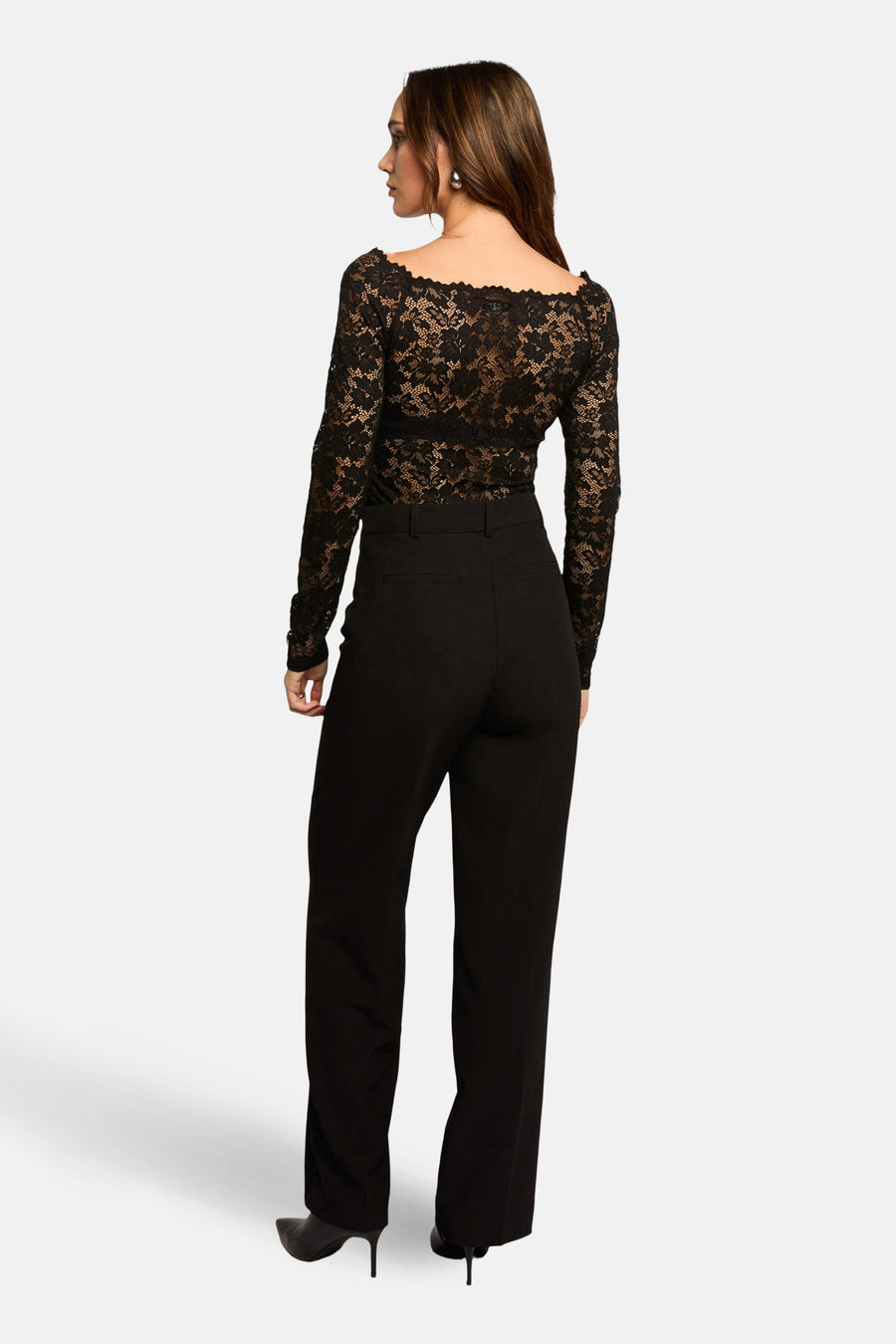 T-shirt noir à manches longues de Morgan de Toi avec motif en dentelle florale, porté avec un pantalon noir et des escarpins noirs.