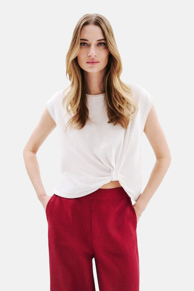 T-shirt blanc à manches courtes de CAROLL, noué sur le devant, porté avec un pantalon rouge.
