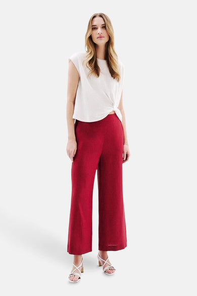 T-shirt blanc à manches courtes de CAROLL, noué sur le devant, porté avec un pantalon rouge.