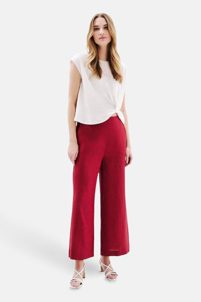 T-shirt blanc à manches courtes de CAROLL, noué sur le devant, porté avec un pantalon rouge.